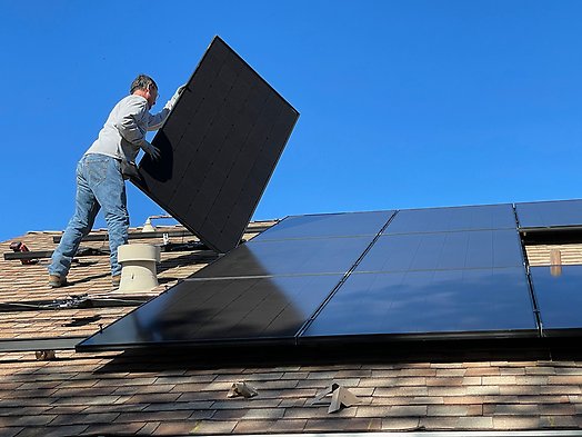 Bild på en man som installerar solpaneler på taket