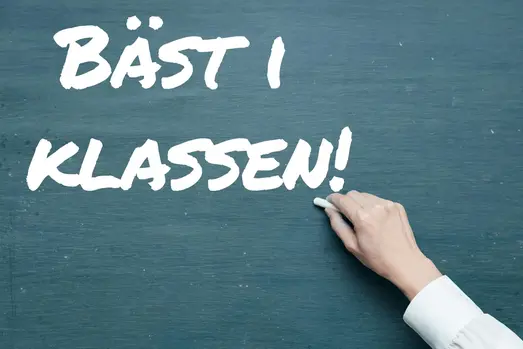 Genrebild: en hand skriver på en skoltavla med texten "Bäst i klassen"